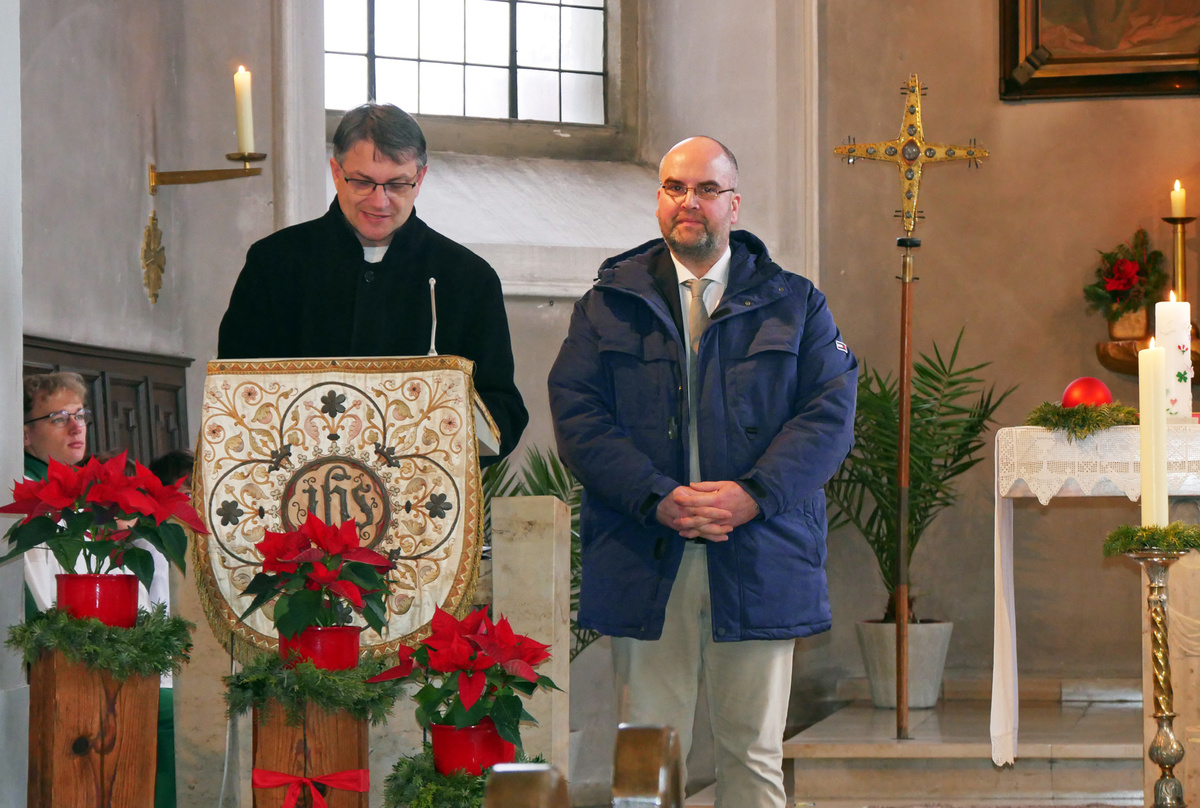 Der Kirchenpfleger und der Restaurator stehen nebeneinander am Ambo der Kirche in Unterpleichfeld.