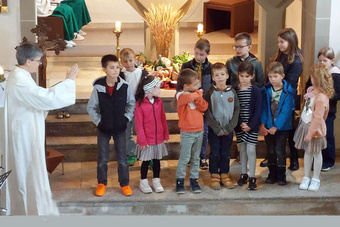 Eine Gruppe mit Kindern steht in der Püssensheimer Kirche. Sie schauen zur Gemeindereferentin hin. Sie ist auf dem Foto links.