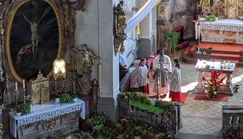 Blick in den Altarraum, wo ein Priester am Ambo steht.