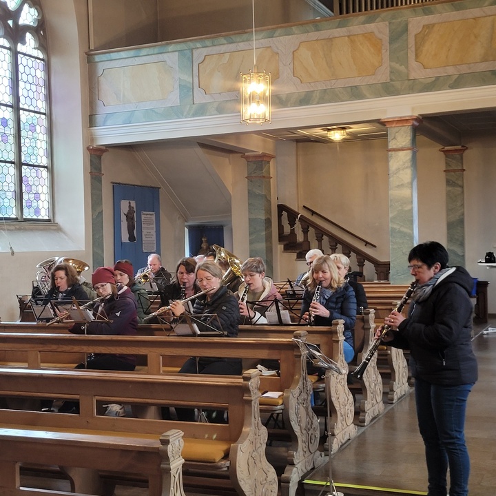 Musiker:innen sitzen in den Kirchenbänken und proben.