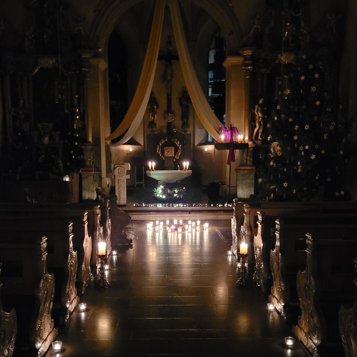 Blick von hinten den Mittelgang entlang zum Altar, die ganze Kirche wird nur durch Kerzenschein erleuchtet