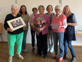 Ein Gruppenbild mit Frau Brand in der Mitte mit Blumen in der Hand.