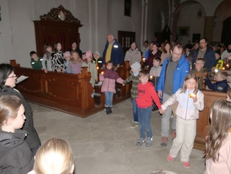 In der Kirche halten sich Kinder und Erwachsene an den Händen und beten