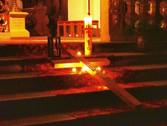 Auf den Altarstufen liegt ein Kreuz. Darum herum sind Kerzen aufgestellt.