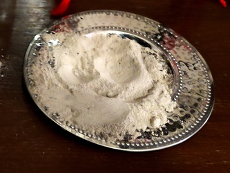 Eine silberne Schale mit Asche darin.