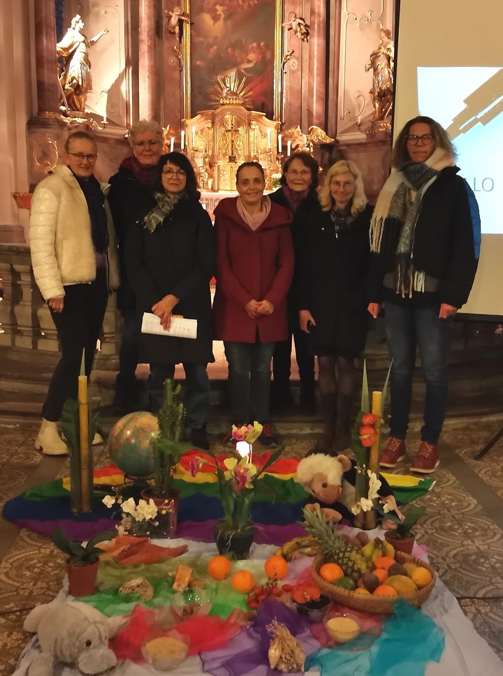 Sieben Frau stehen im Altarraum der Kirche. Vor ihnen einen Bodenbild, gestaltet mit bunten Tüchern, Früchten und Stofftieren.