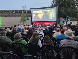 Blick von hinten auf die Leinwand und die Leute, die davor sitzen und den Film schauen.