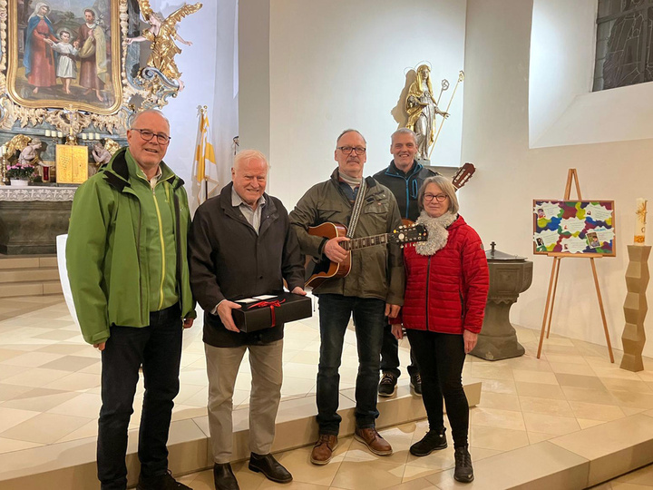 Vier Personen stehen im Altarraum der Riedener Kirche und lächeln in die Kamera.