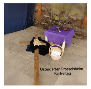 Ein Kreuz mit einem schwarzen Tuch, daneben auf einem kleinen Tisch Hammer und Nägel als Symbol für den Karfreitag.