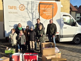 Vor einem Lieferwagen der Würzburger Tafel stehen Menschen und heben ihren Daumen hoch.