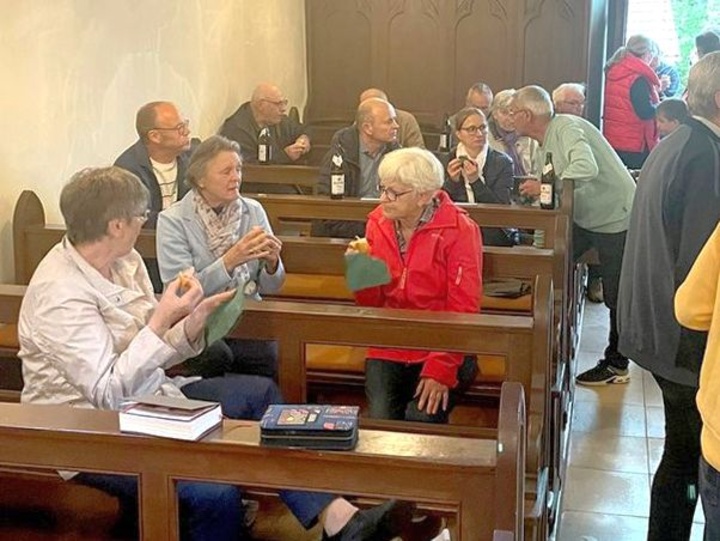 In den Kirchenbänken sitzen Menschen und unterhalten sich.