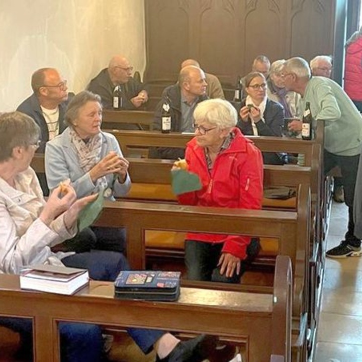 In den Kirchenbänken sitzen Menschen und unterhalten sich.