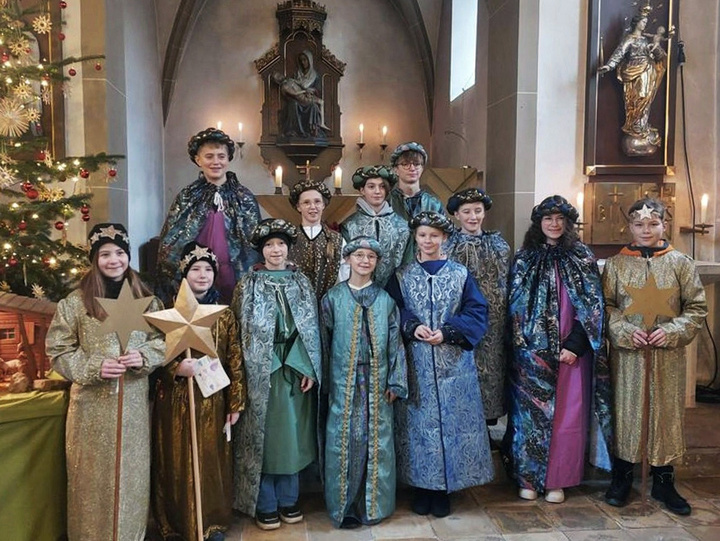 Eine Gruppe von Kindern und Jugendlichen schaut in die Kamera. Sie sind als Sternsinger angezogen.