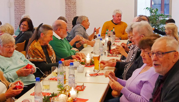 Senioren sitzen um einen Tisch und singen