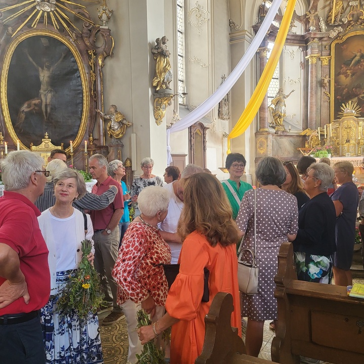 Viele Menschen stehen in einer festlich geschmückten Kirche.