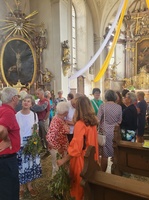 Viele Menschen stehen in einer festlich geschmückten Kirche.