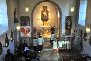 Blick von der Empore in die Kirche, wo der liturgische Dienst vorm Altar steht.