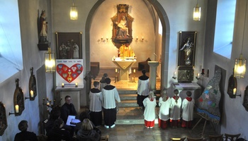 Blick von der Empore in die Kirche, wo der liturgische Dienst vorm Altar steht.