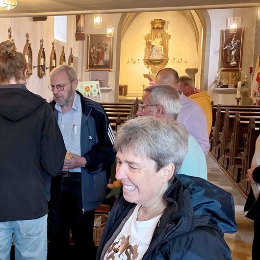In der Kirche sitzen und stehen Menschen. Sie essen etwas und unterhalten sich.