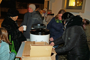 Auf dem Kirchplatz stehen Menschen um einen großen Topf mit Glühwein.