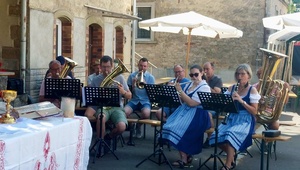 Das Bild zeigt eigen Blaskapelle aus 10 Personen. Die Frauen im Vordergrund haben blaue Dirndl an.