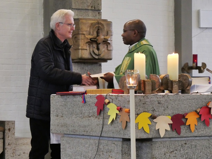 Heinz Zimmermann und Father Dunstan geben sich die Hand. Das Foto ist in der Kirche aufgenommen. Man sieht den Altar.