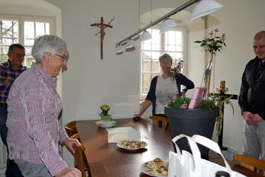Um einen Tisch im Pfarrhaus stehen vier Personen. Vorne links ist Auguste Weber. Sie lacht.