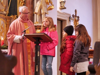 Am Ambo spricht ein Kommunionkind ins Mikrofon. Links von ihr steht Pfarrer Rüdamer, rechts sind zwei weitere Kinder.