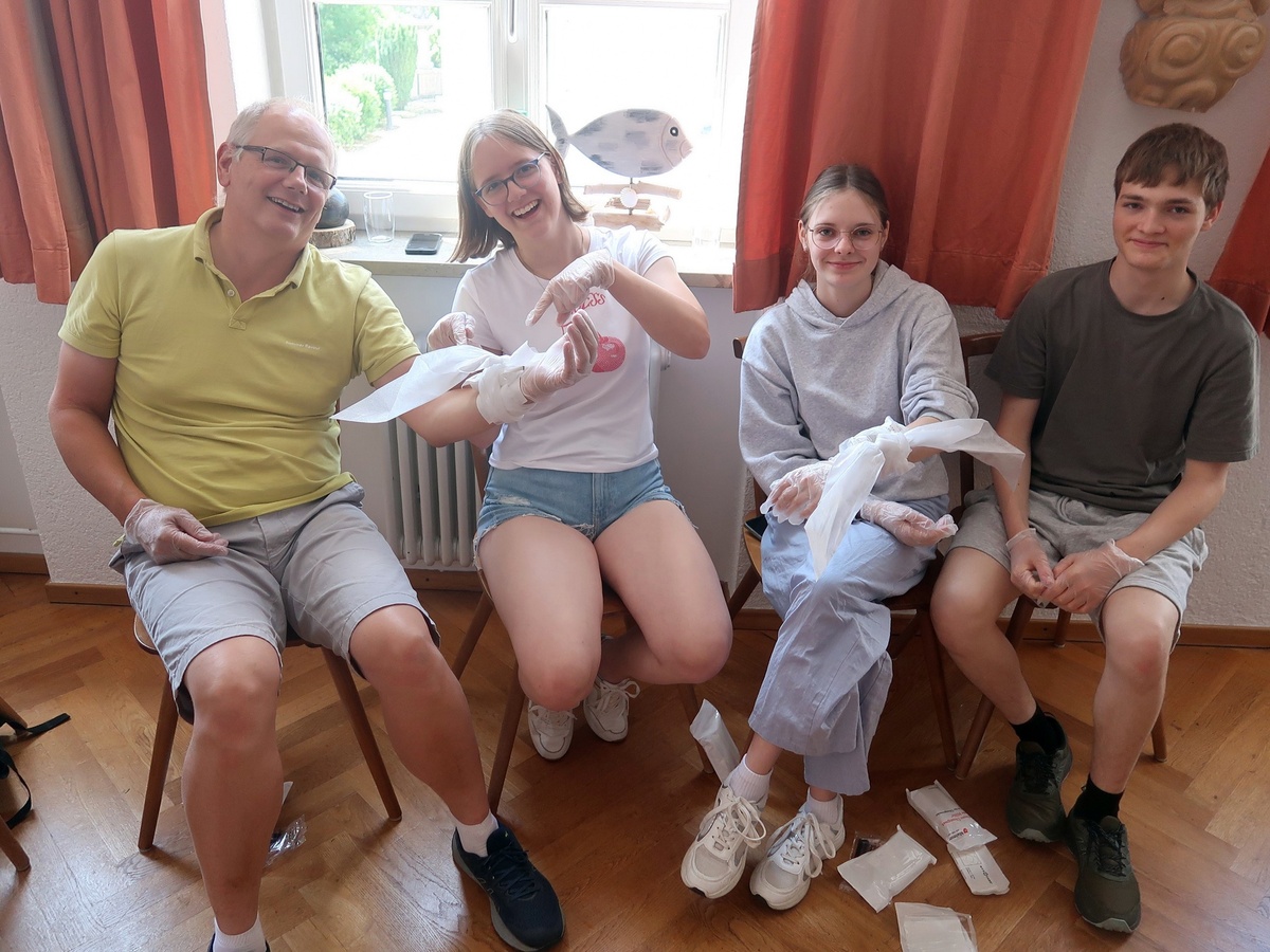 Vier Personen üben Verbände. Sie sitzen nebeneinander.