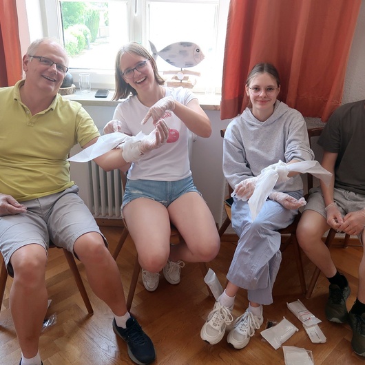 Vier Personen üben Verbände. Sie sitzen nebeneinander.