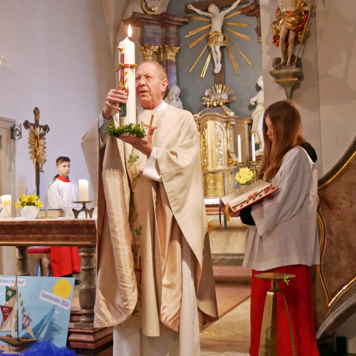 Pfarrer Zapff hält die geschmückte Osterkerze in den Händen und zeigt sie den Gottesdienstbesuchenden.