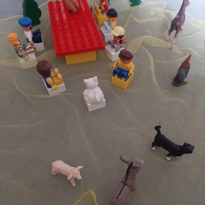 Lego-Figuren sitzen um einen Tisch. Um sie herum sind mehrere Tiere