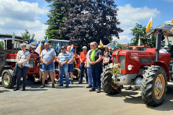 Menschen stehen vor ihren Traktoren und sind still. Sie hören dem Segensgebet zu.