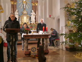 Am Ambo und am Altar der Kirche stehen drei Personen, die etwas vorlesen.