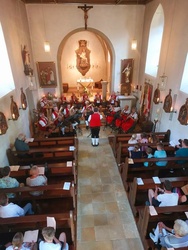 Aufnahme des Kirchenraums mit gefüllten Bänken und der Musikkapelle im Altarraum.