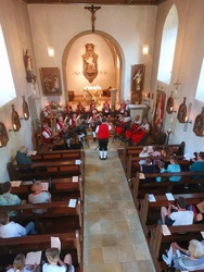 Aufnahme des Kirchenraums mit gefüllten Bänken und der Musikkapelle im Altarraum.