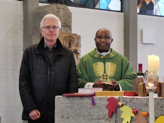 Zwei Männer stehen nebeneinander hinter dem Altar der Kirche und schauen freundlich in die Kamera.