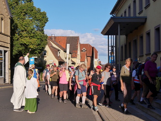 Die Kreuzbergwallfahrenden auf den Stufen zur Kirche in Bergheim. Pastoralreferent Meier besprengt sie mit Weihwasser.