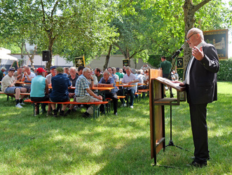 Am Rednerpult spricht Eberhard Nuß. Vor ihm sieht man sitzende Menschen, die ihm zuhören.