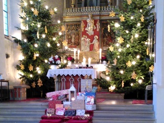 Die weihnachtliche Kirche in Opferbaum. Auf den Altarstufen liegen verpackte Weihnachtsgeschenke.