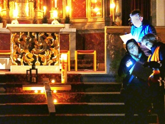 Auf den Altarstufen liegt das Holzkreuz. Darum herum sind Kerzen aufgestellt.