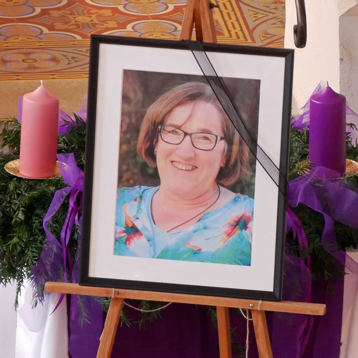 Ein gerahmtes Bild mit Trauerschleife steht vor dem Adventskranz in der Kirche.