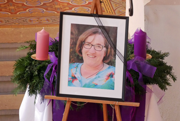 Ein gerahmtes Bild mit Trauerschleife steht vor dem Adventskranz in der Kirche.