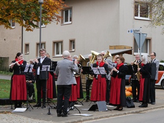 Blick auf eine Musikkapelle in schwarz-roter Tracht. Die Musikantinnen und Musikanten spielen gerade ihr Instrument.