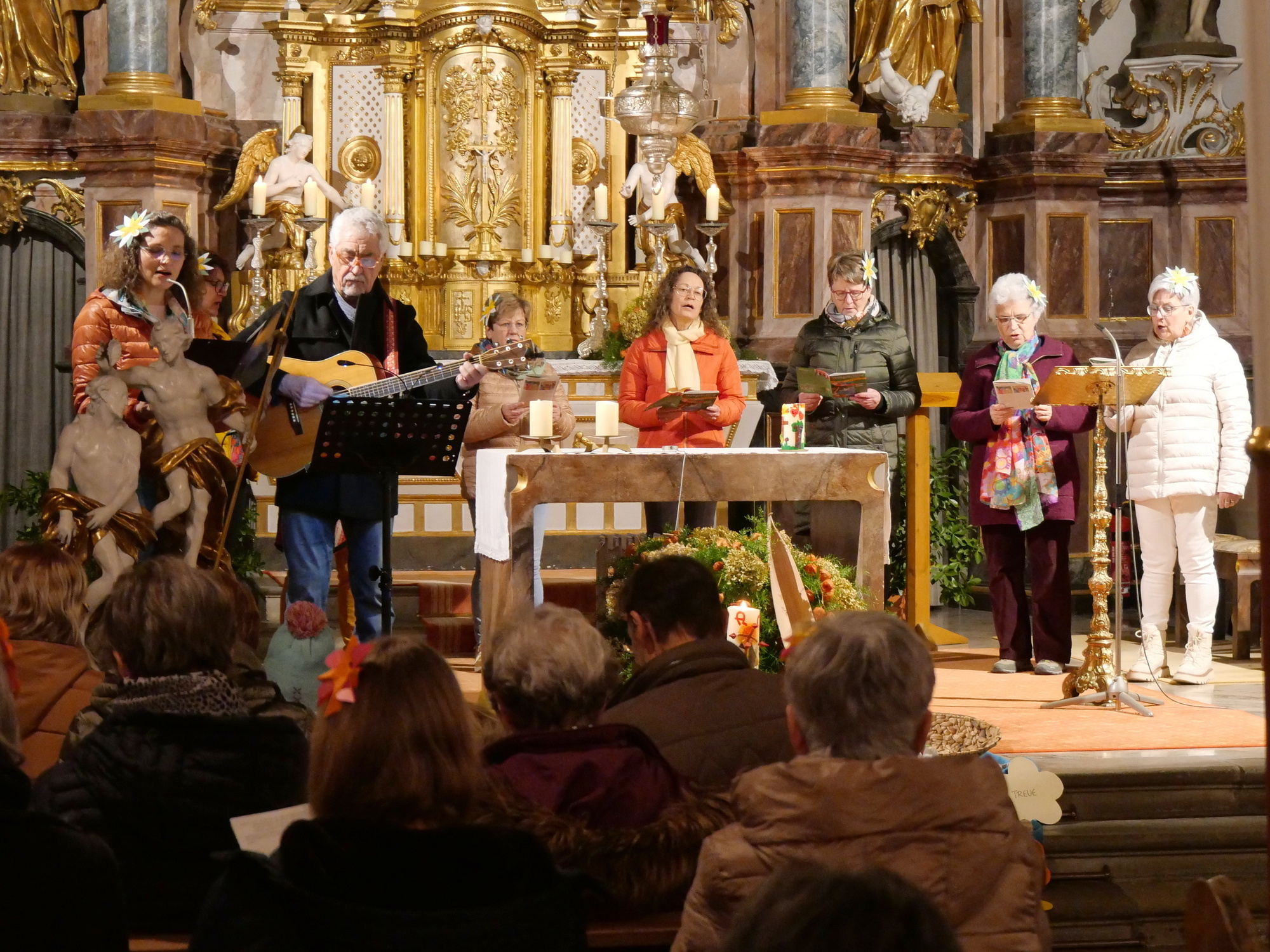 Foto von hinten in der Kirche nach vorn in den Altarraum. Dort steht eine Gruppe Menschen.