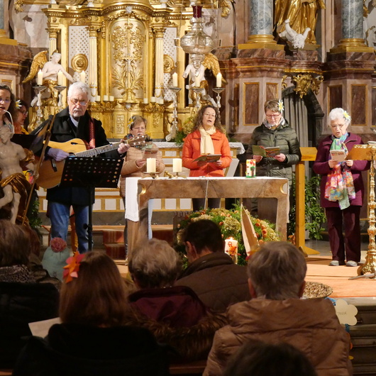 Foto von hinten in der Kirche nach vorn in den Altarraum. Dort steht eine Gruppe Menschen.