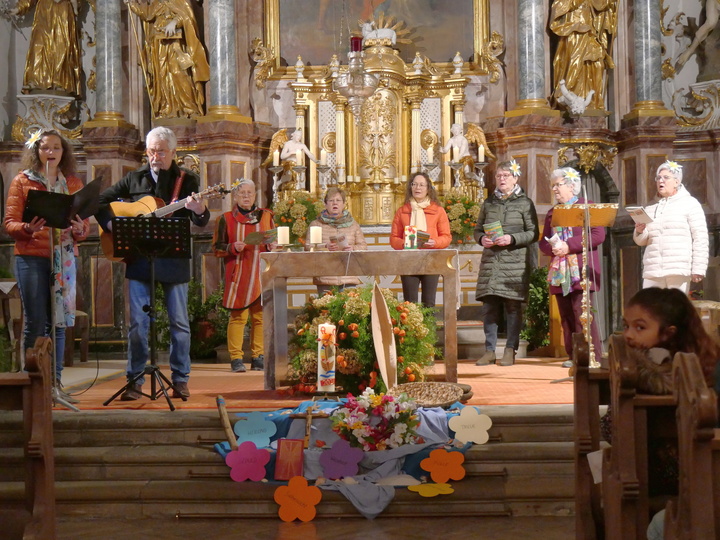 Blick vom Mittelgang in der Kirche in den Altarraum. Hier steht eine Gruppe Menschen.