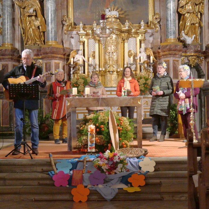 Blick vom Mittelgang in der Kirche in den Altarraum. Hier steht eine Gruppe Menschen.