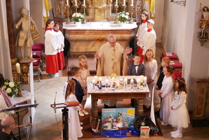 Blick von der Orgel in den Altarraum der Hausener Kirche. Um den Altar stehen der Pfarrer und die Kommunionkinder.