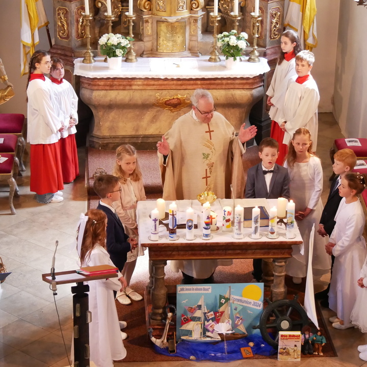 Blick von der Orgel in den Altarraum der Hausener Kirche. Um den Altar stehen der Pfarrer und die Kommunionkinder.